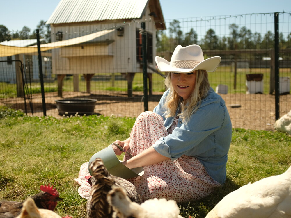 Sarah sitting with her backyard flock on the homestead