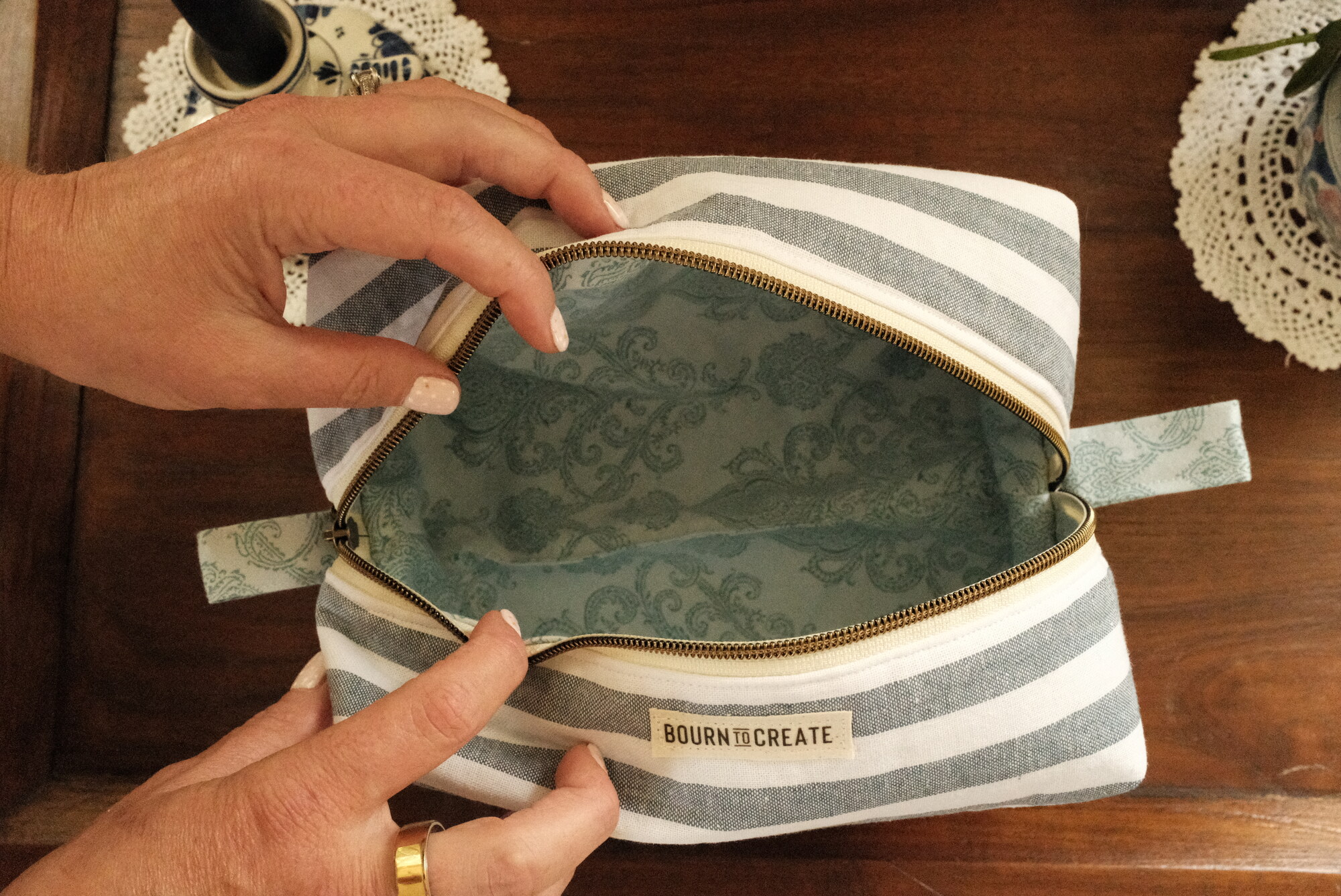 Boxy zip makeup bag in the seaside stripe, open to show the paisley lining