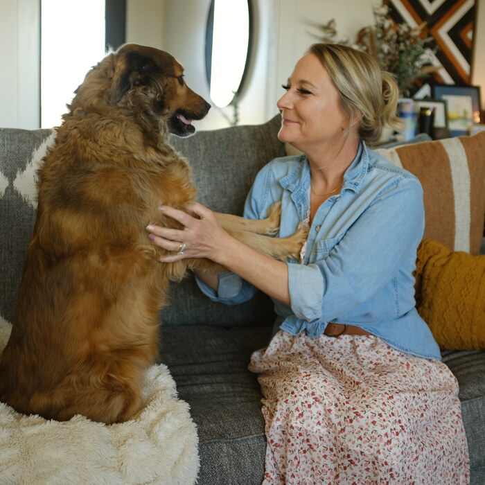 Sarah on the couch beside a big fluffy dog
