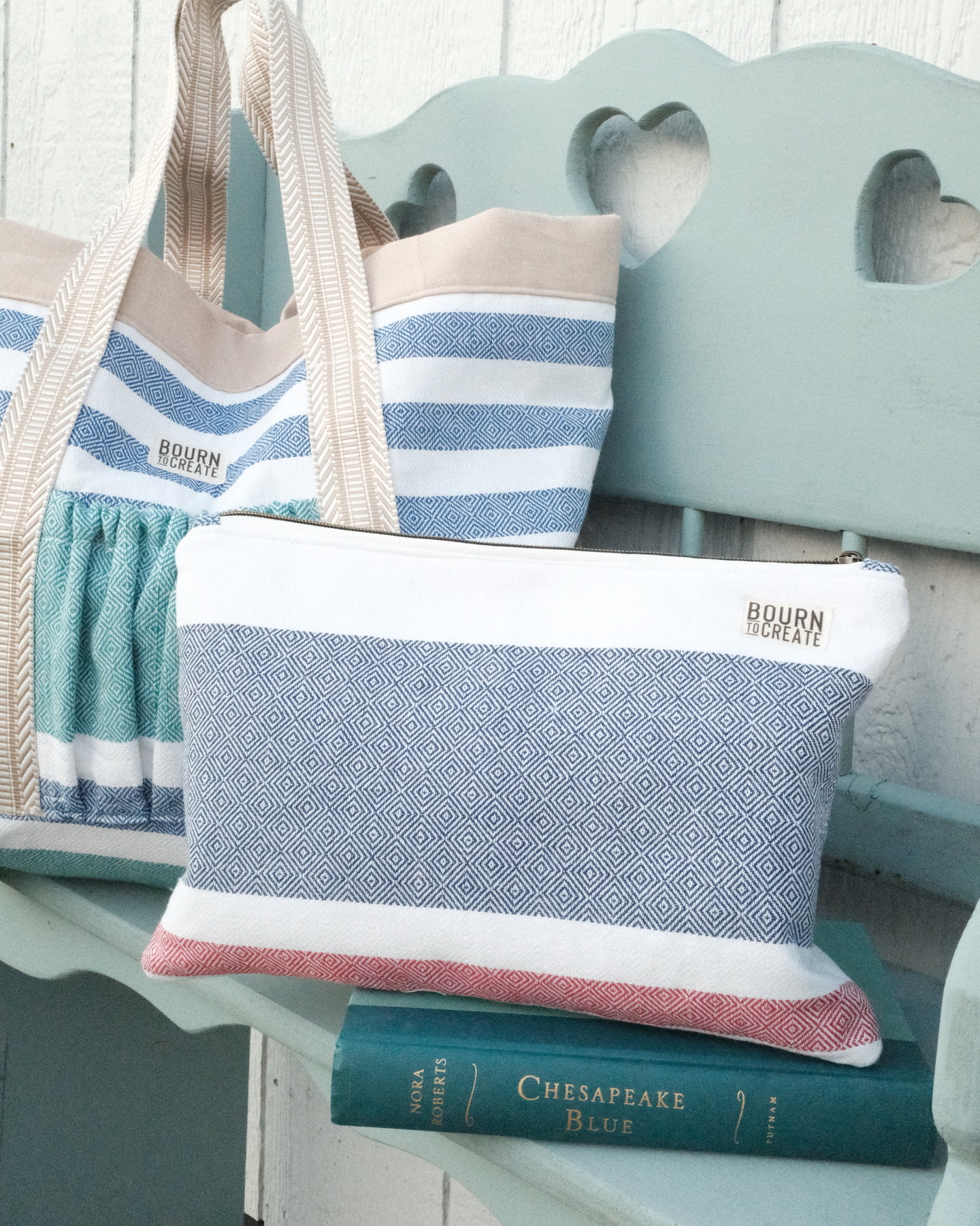 A hand-sewn striped zip pouch and matching tote from the monthly drop, resting on a mint bench